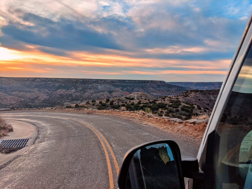 View from a van window, driving through a desert setting
