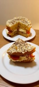 slice of victoria sponge with fresh cream and strawberries and grated chocolate on the top
