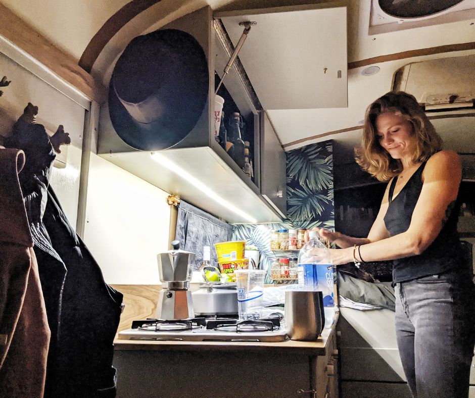 Ayana in the bus kitchen with a bottle of water