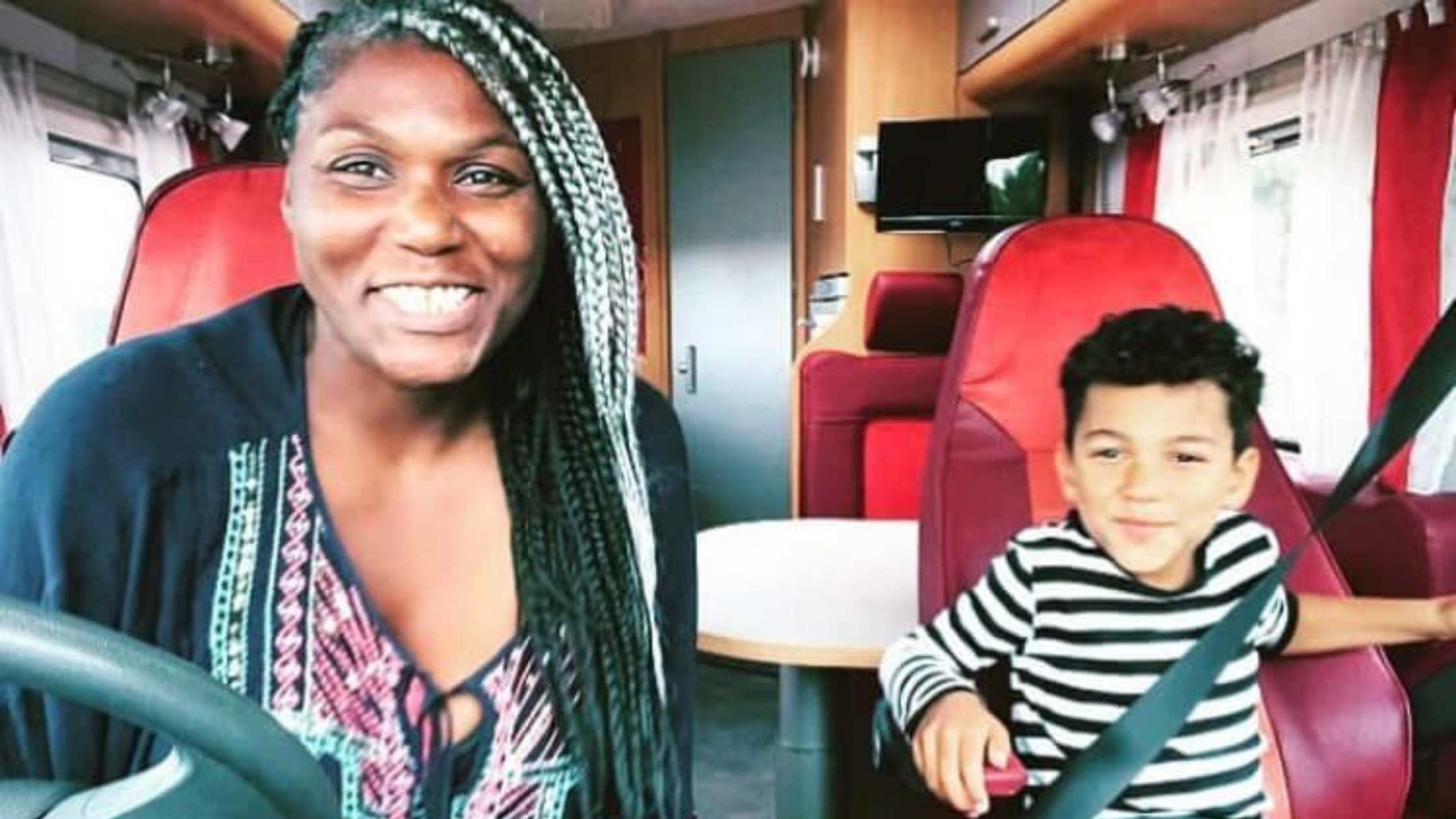Delaine and Quincy are ready for adventure sitting in the front seats of their motorhome. Both are smiling