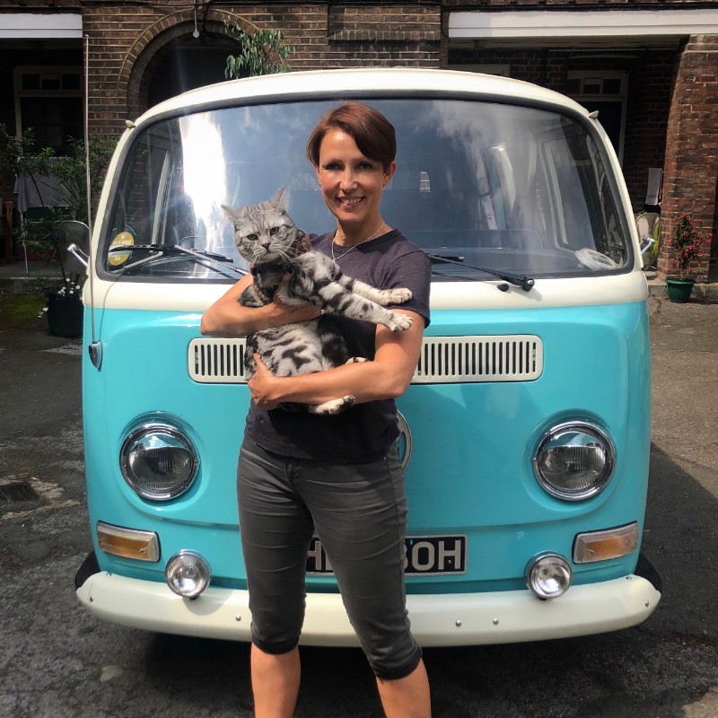 Janey holding her cat in front of her campervan